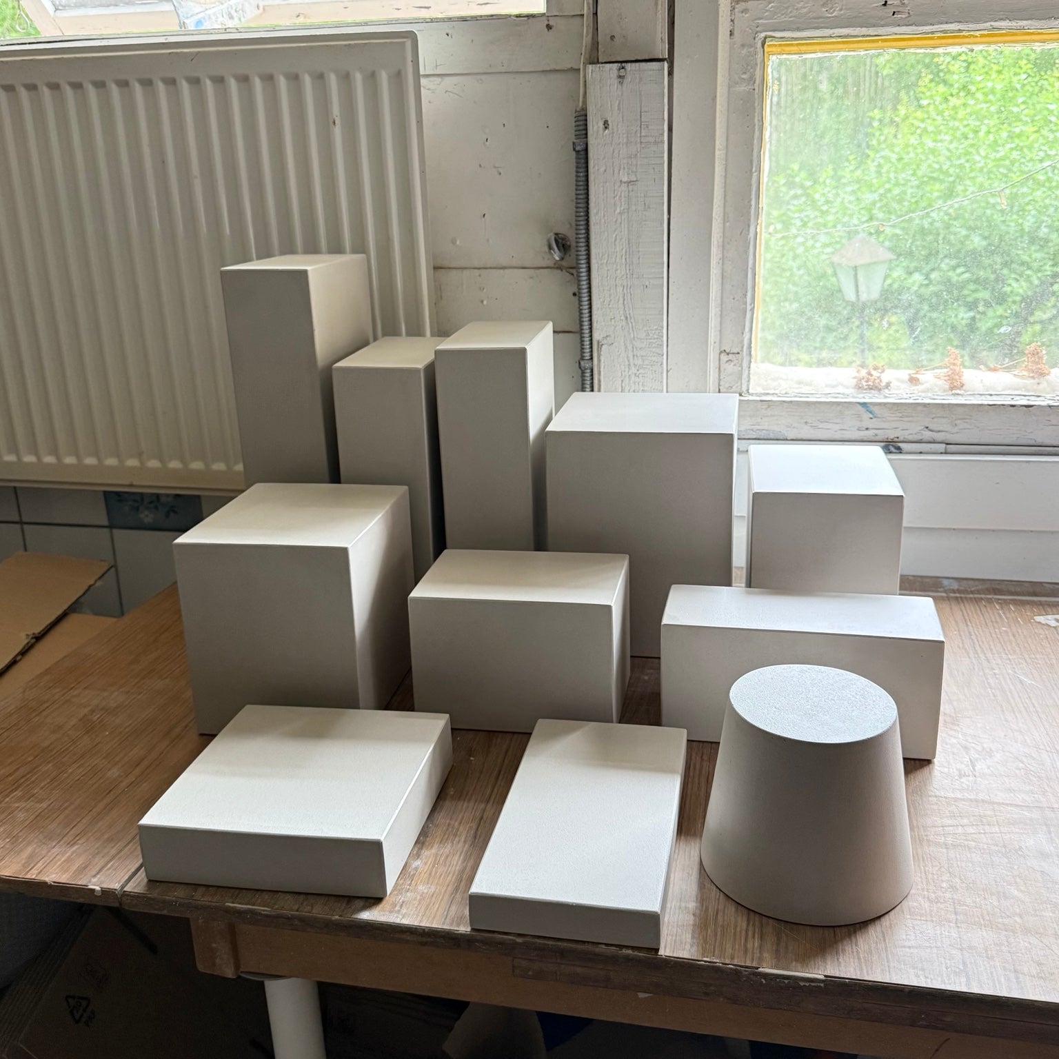 Warm-grey and ivory matte geometric display blocks showing soft low-glare surfaces