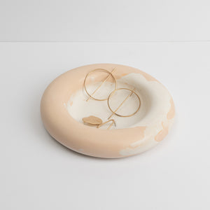A beige-colored round acrylic prop with a smooth surface, used for displaying jewelry such as earrings.