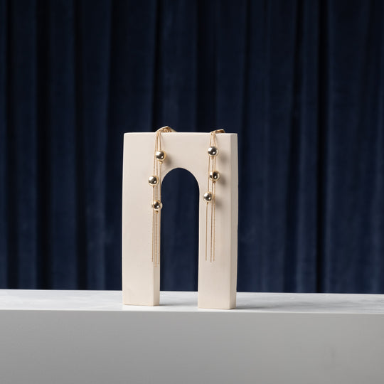 Sculptural arch styling form in light mineral plaster with draped jewelry for editorial product photography