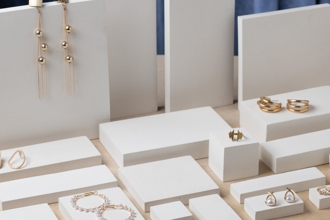 Set of jewelry display stands with gold jewelry on a neutral background