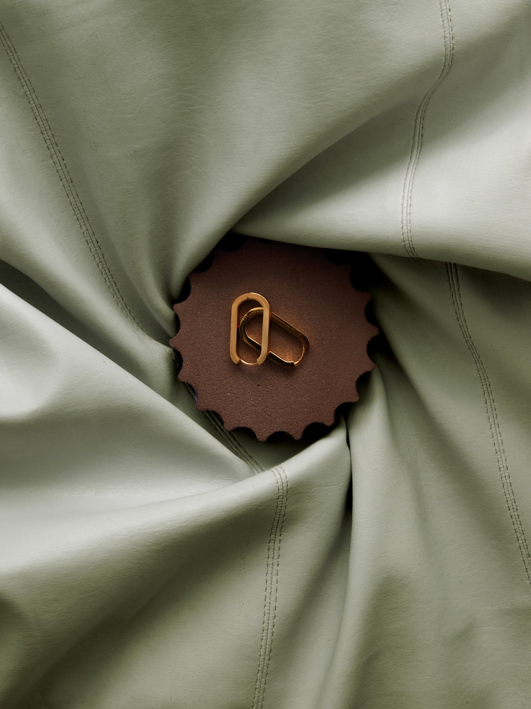 Gold earrings on a textured mineral display surface for an editorial lookbook