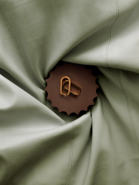 Gold earrings on a textured mineral display surface for an editorial lookbook