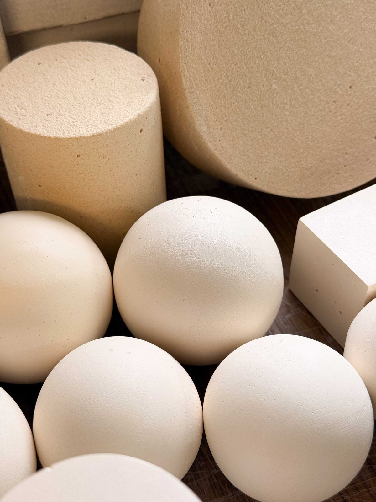 Collection of handmade Betonvton spheres, cylinders and blocks showing real mineral texture in warm neutral tones