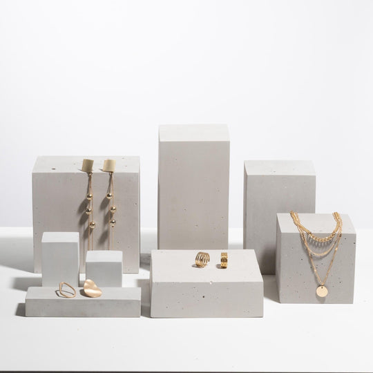 Gold jewelry displayed on light grey concrete display blocks