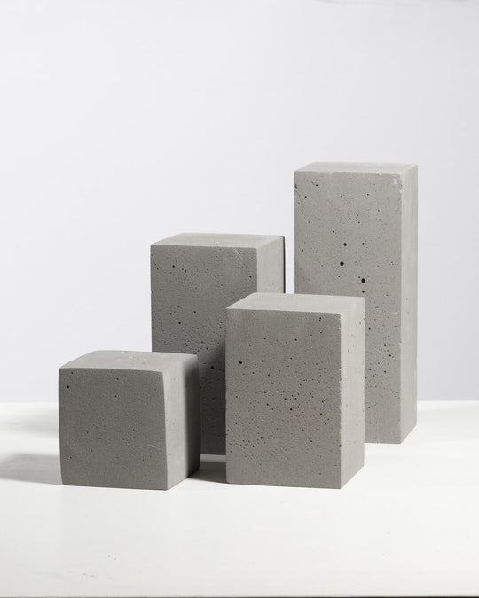 Set of four grey concrete display blocks of varying heights with porous textured surface