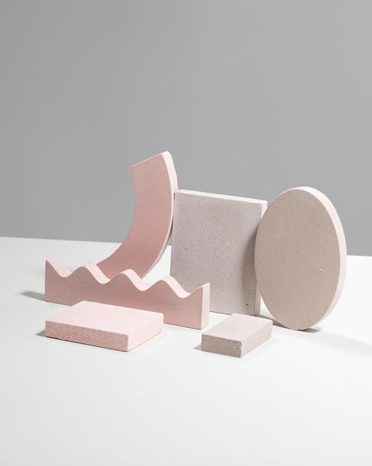 Six geometric display props in pale pink and light beige, arch, block, oval disc and wavy base