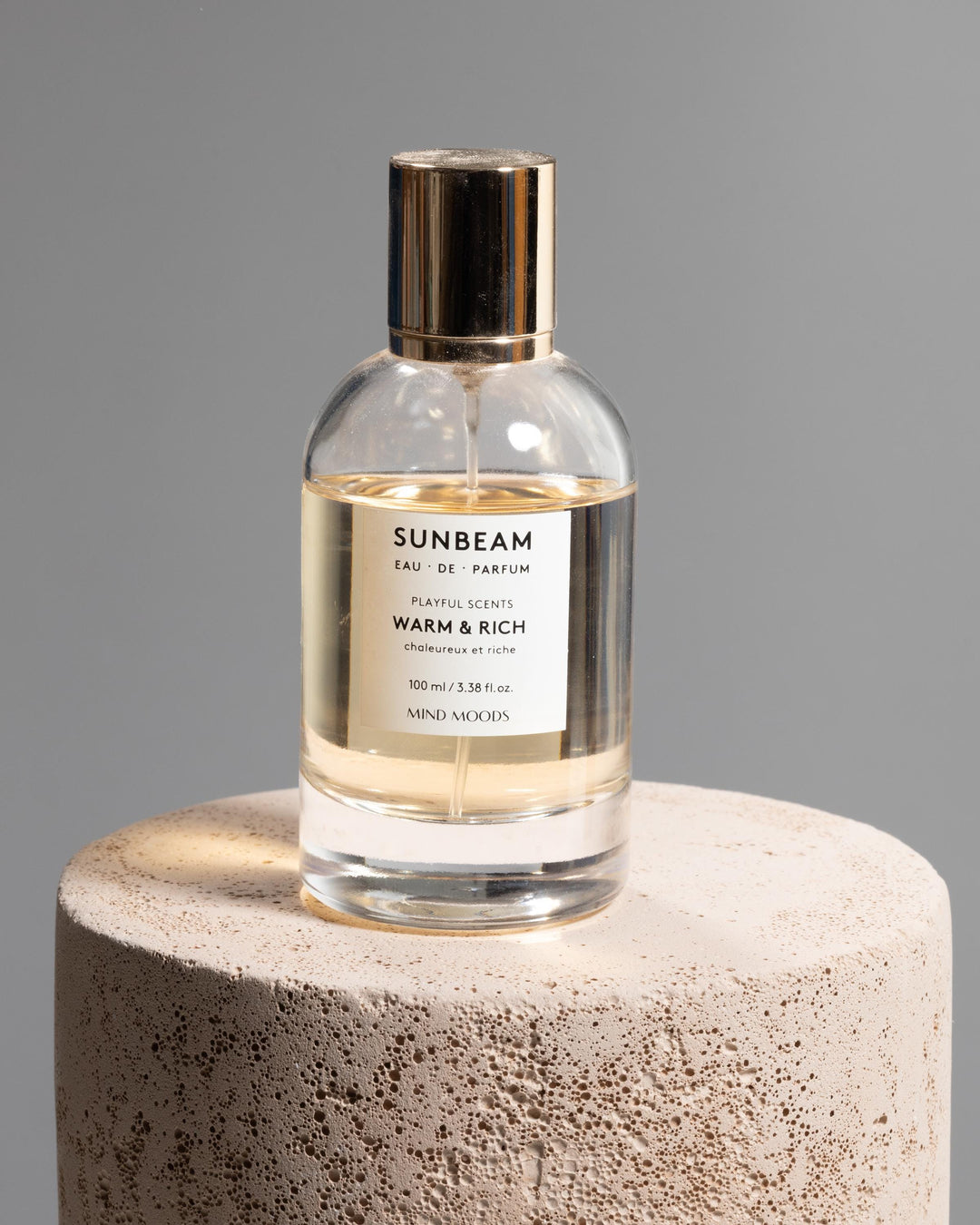 Perfume bottle styled on textured sand beige cylinder podium