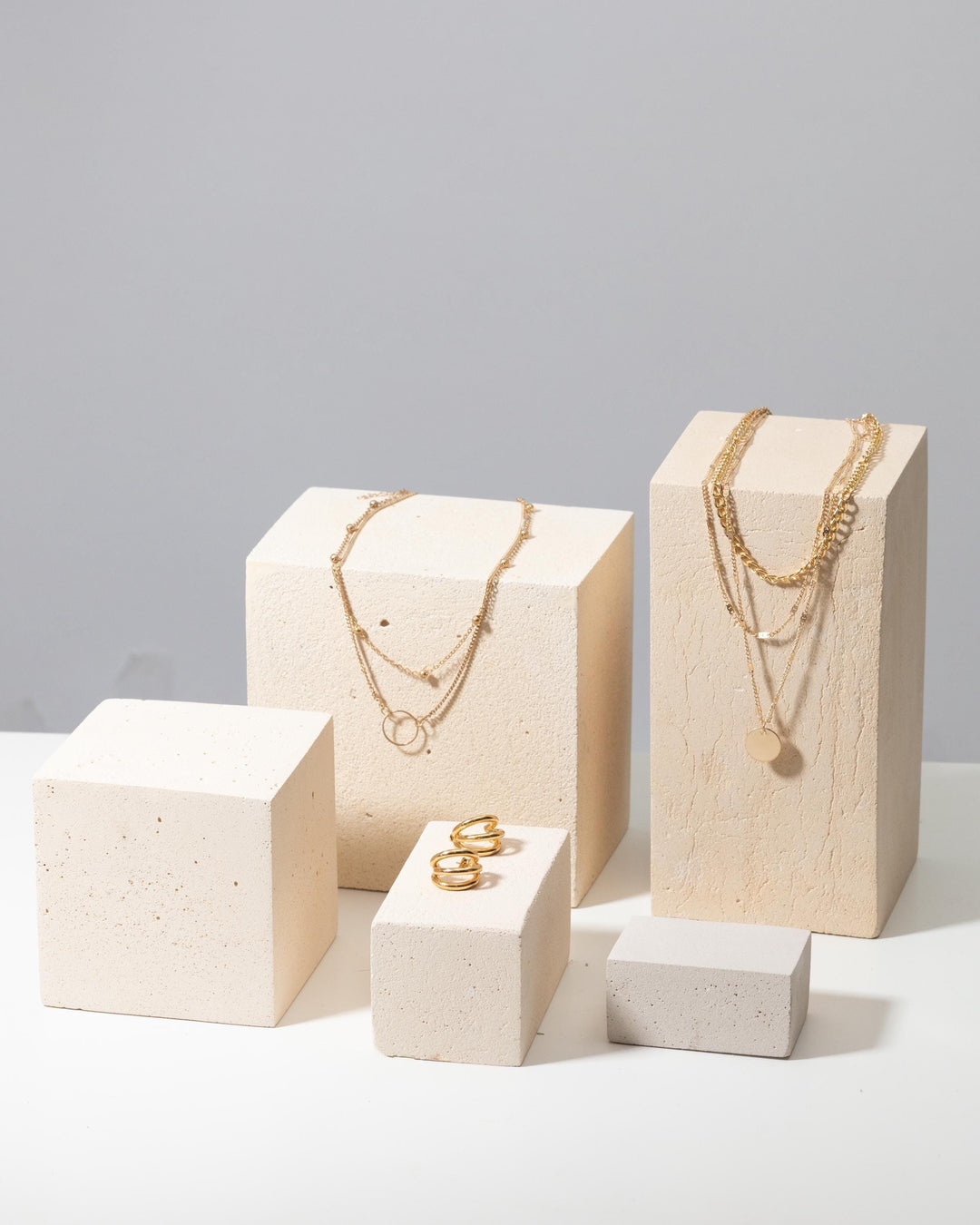 Large concrete product display blocks styled with gold jewelry