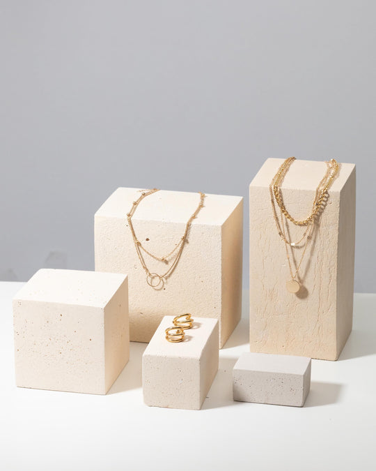 Large concrete product display blocks styled with gold jewelry