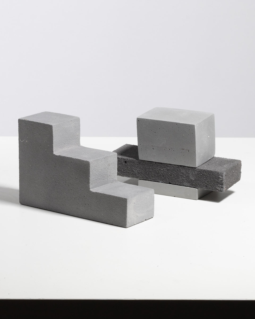 Grey plaster step riser with stacked rectangular display blocks, matte mineral finish