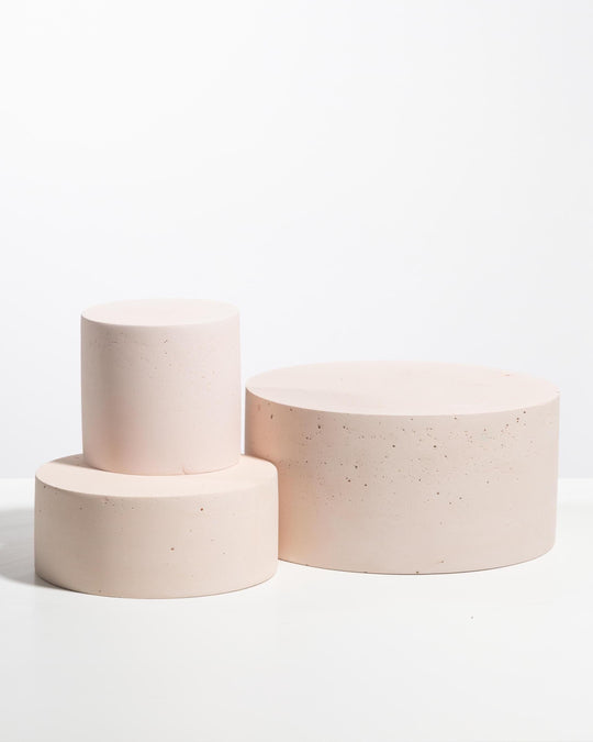 Three blush pink plaster cylinder pedestals of different heights for product display