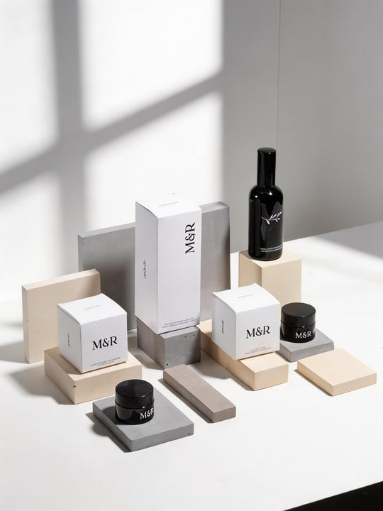 Neutral display risers styled with M and R skincare packaging on concrete and beige blocks