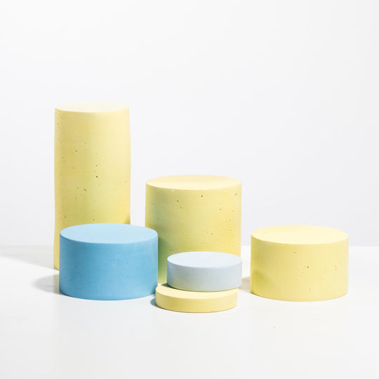 Set of six cylindrical display pedestals in pastel yellow and light blue with matte finish