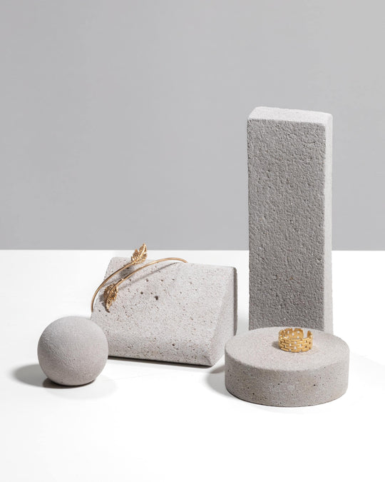 Mineral concrete jewelry display set in warm grey with slab, arch block, sphere and disc platform styled with gold bracelet and ring
