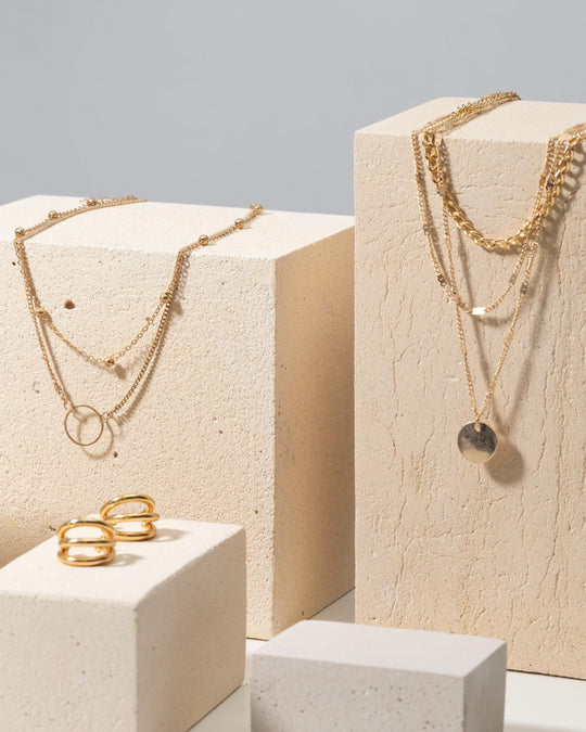Concrete display blocks styled with layered gold necklaces and rings