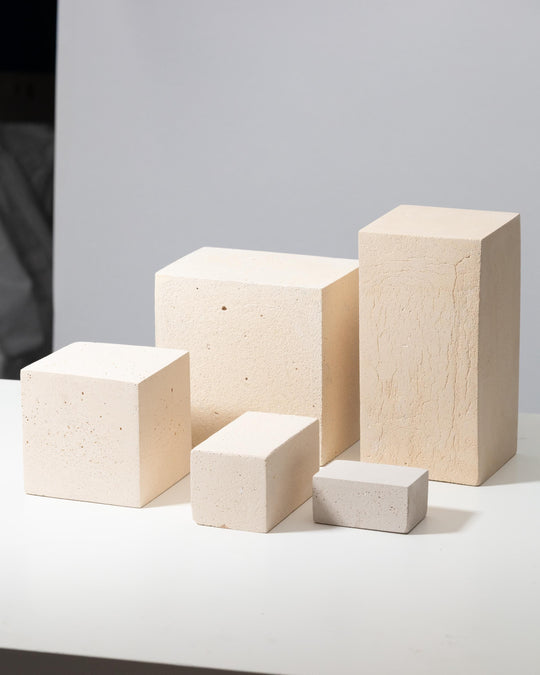 Five off-white concrete display blocks with porous matte texture