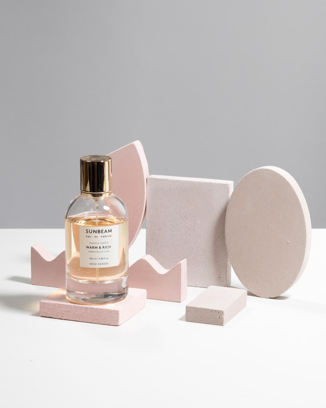 Modular display set styled with perfume bottle on pink rectangular block surrounded by geometric shapes