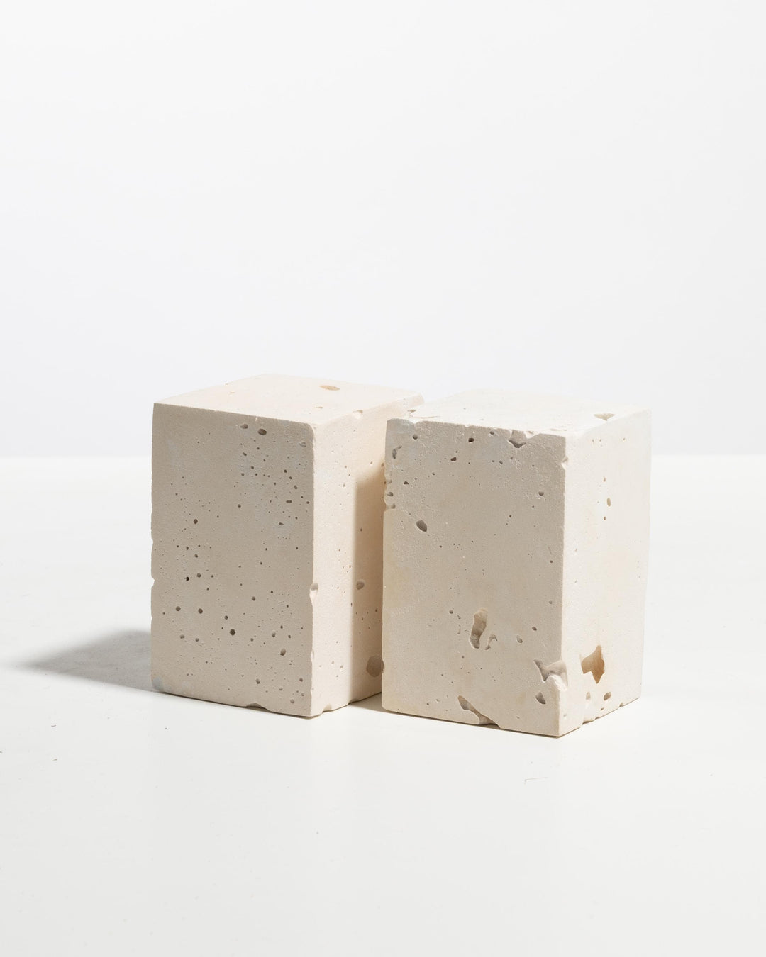Two ivory plaster rectangular display blocks with porous mineral texture