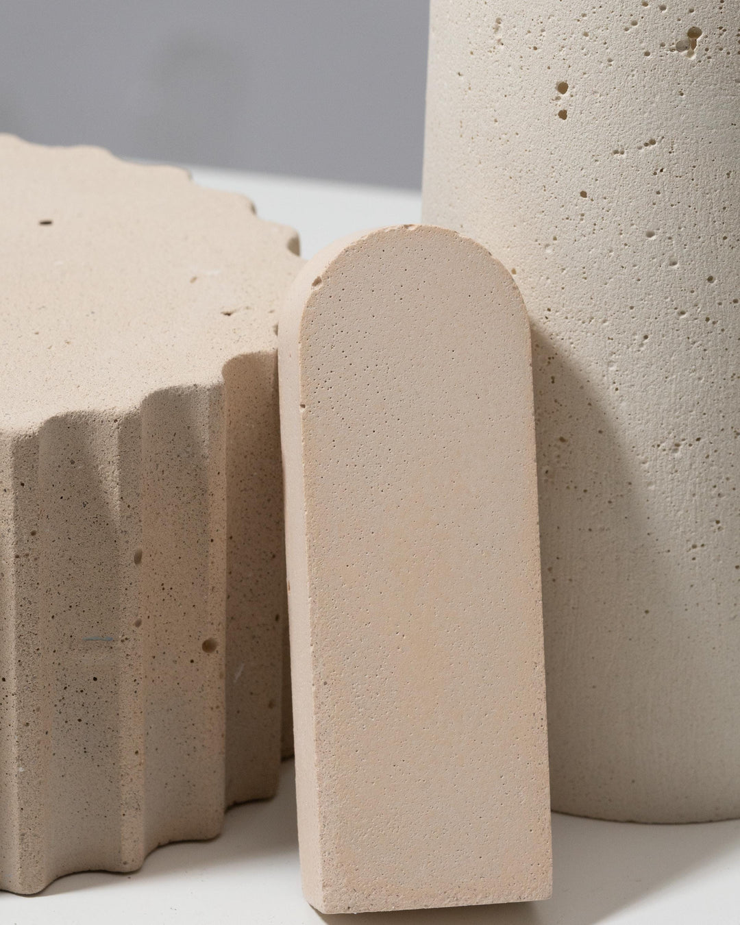 Set of three beige plaster pieces: cylinder pillar, fluted pedestal and arch