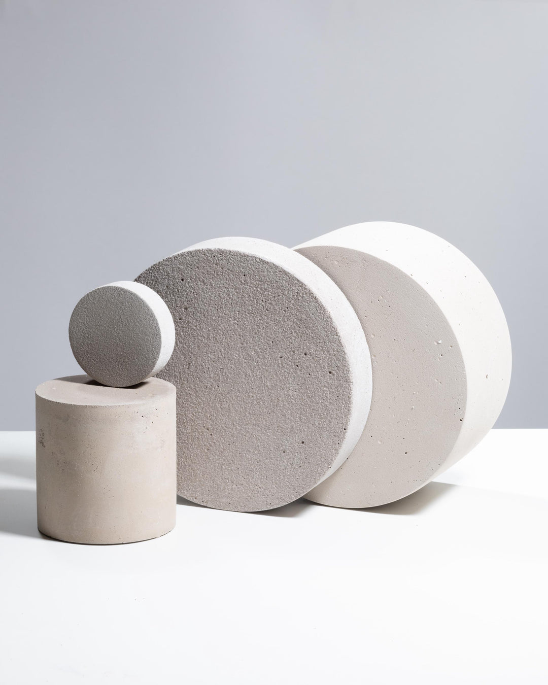 Four grey plaster display pedestals with discs and cylinder clustered