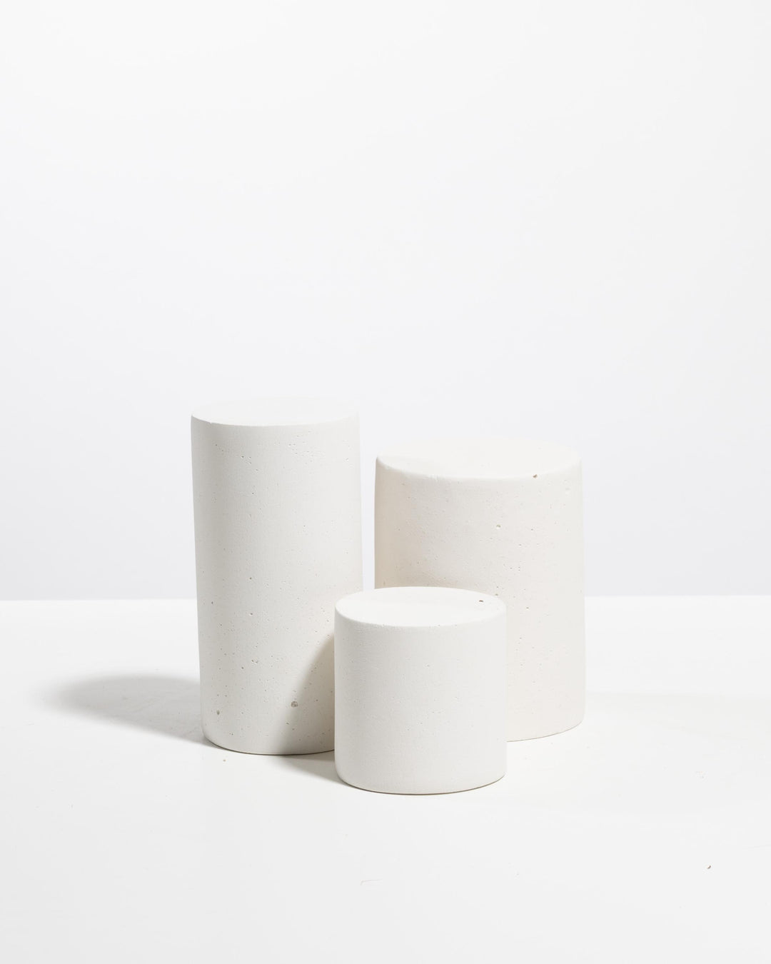 Three off white cylinder display pedestals in graduated heights