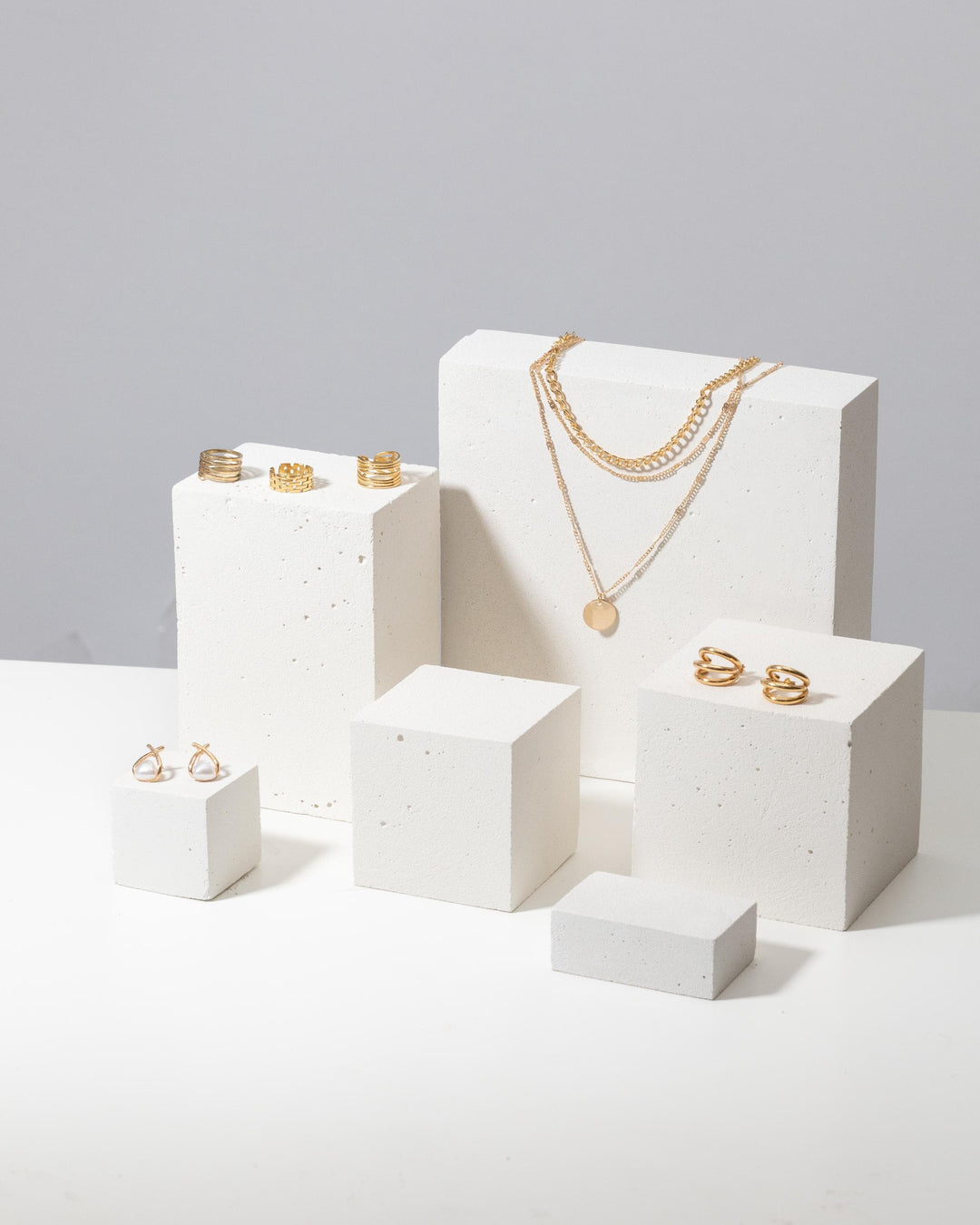 Gold jewelry styled on white textured display blocks