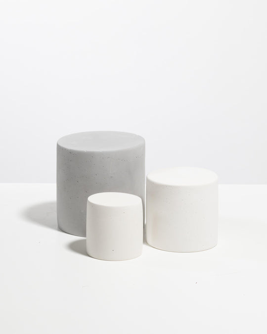 Three cylinder display pedestals in white and light grey with speckled plaster texture