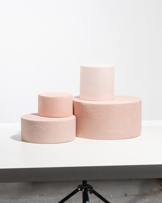 Three stacked cylindrical display pedestals in soft pale pink